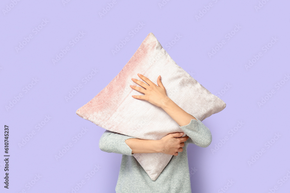 Woman with cushion near lilac wall