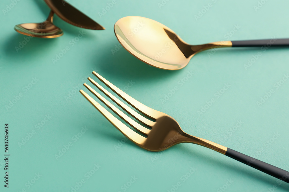 Stylish fork and spoon on green background