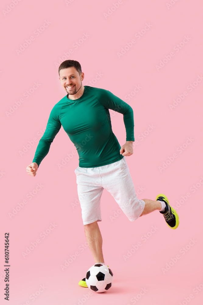 Man playing with soccer ball on pink background