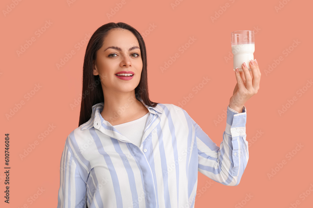 Beautiful young woman with glass of milk on beige background