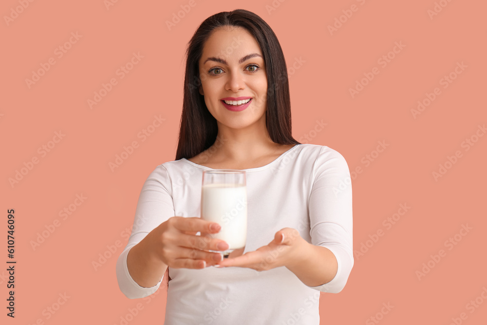 Beautiful young woman with glass of milk on beige background