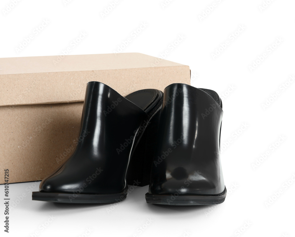 Cardboard box with stylish black heeled shoes on white background