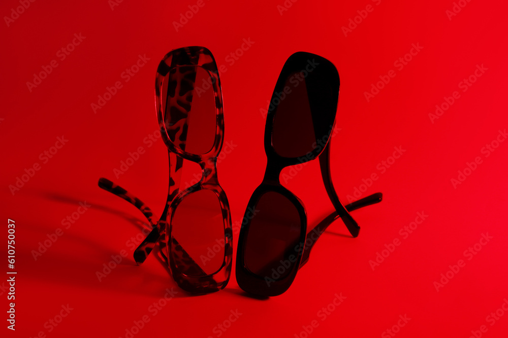 Different stylish sunglasses on red background