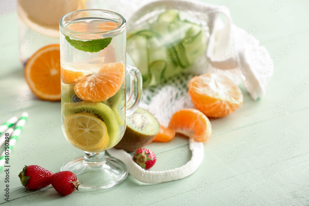 Glass of infused water with different sliced fruits on grey table