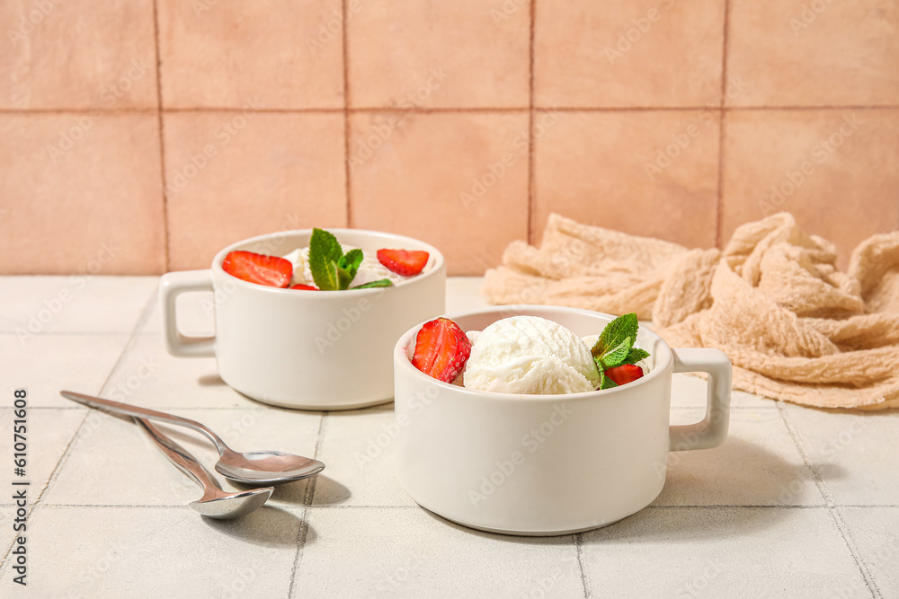 Bowls of strawberry ice cream and spoons on white tile table