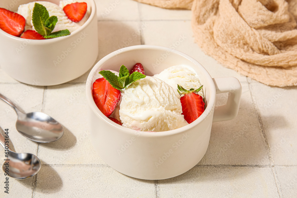 Bowls of strawberry ice cream and spoons on white tile table, closeup