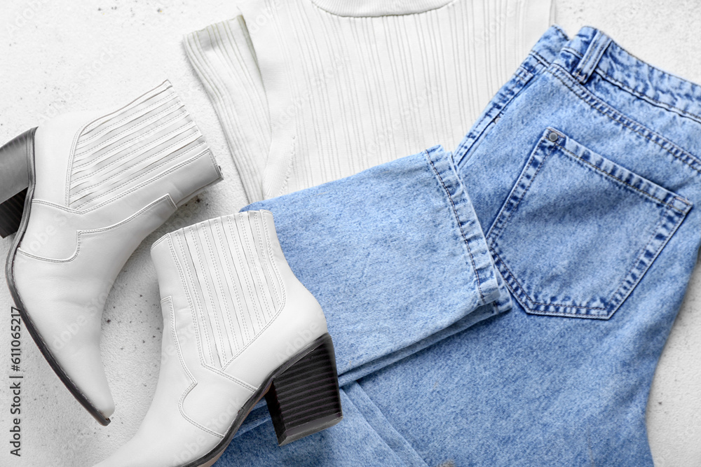 Stylish jeans with vest and boots on white background, closeup