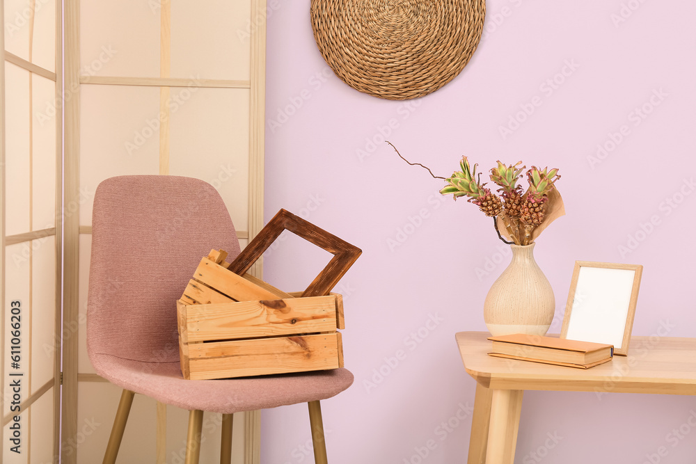 Vase with baby pineapples, book and frame on table in interior of living room