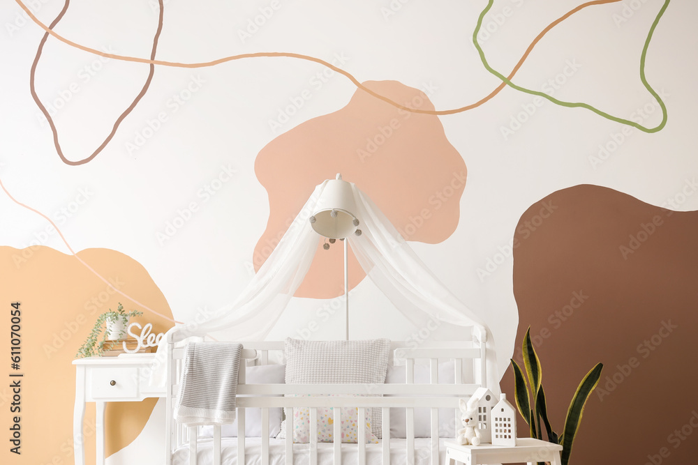 Interior of stylish bedroom with baby crib, lamp and table