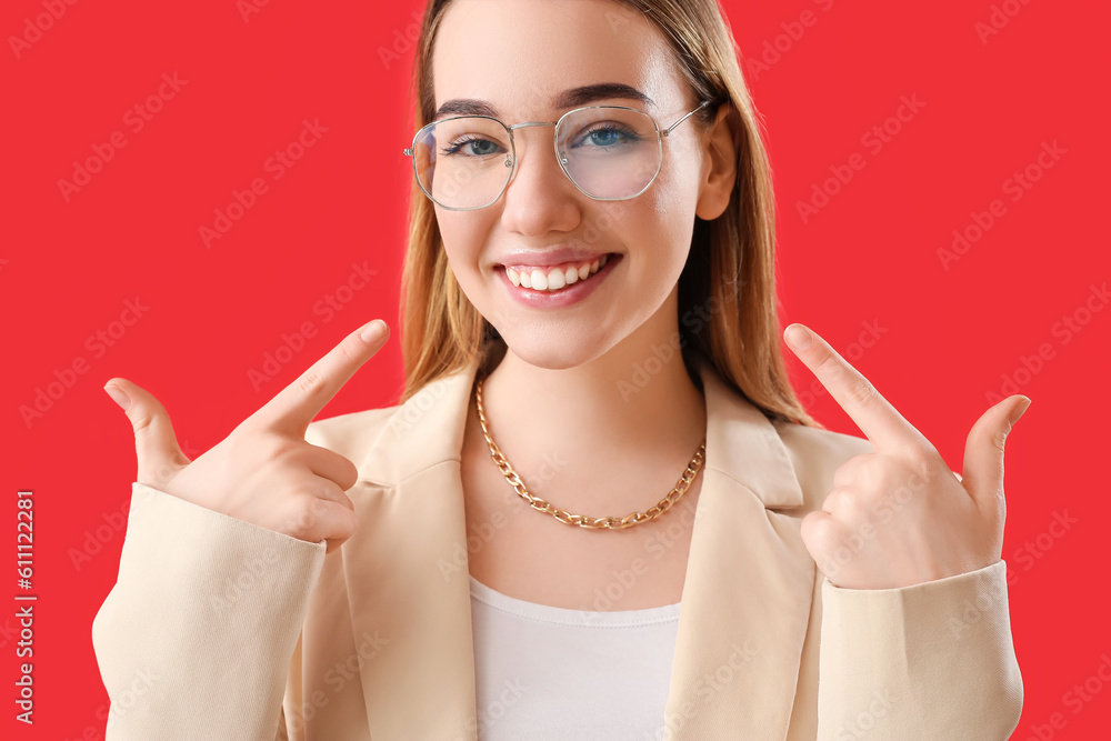 Young businesswoman pointing at her smile on red background, closeup