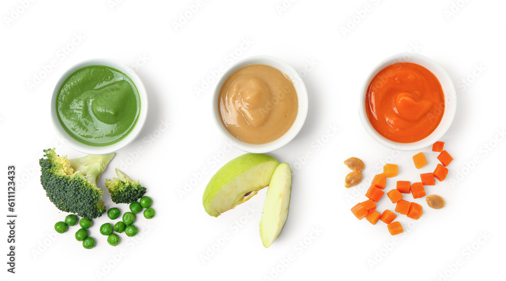 Bowls with healthy baby food and fresh vegetables on white background