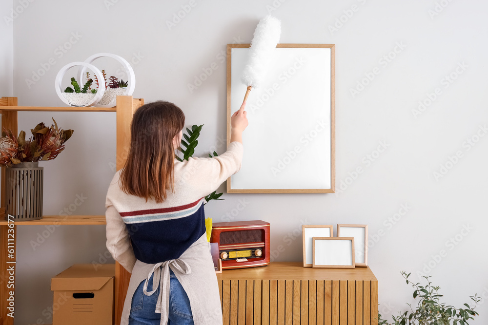 Housewife cleaning blank frame with pp-duster at home