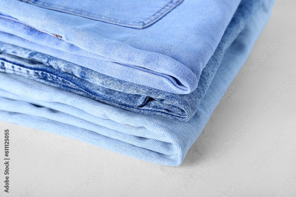 Folded jeans on white background, closeup