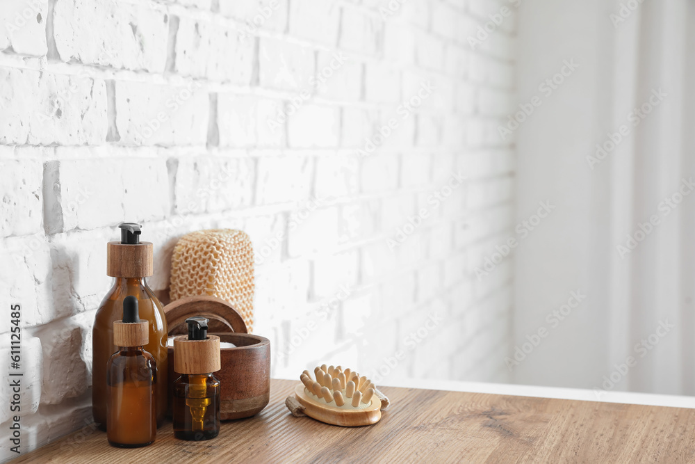 Bath accessories on table near white brick wall