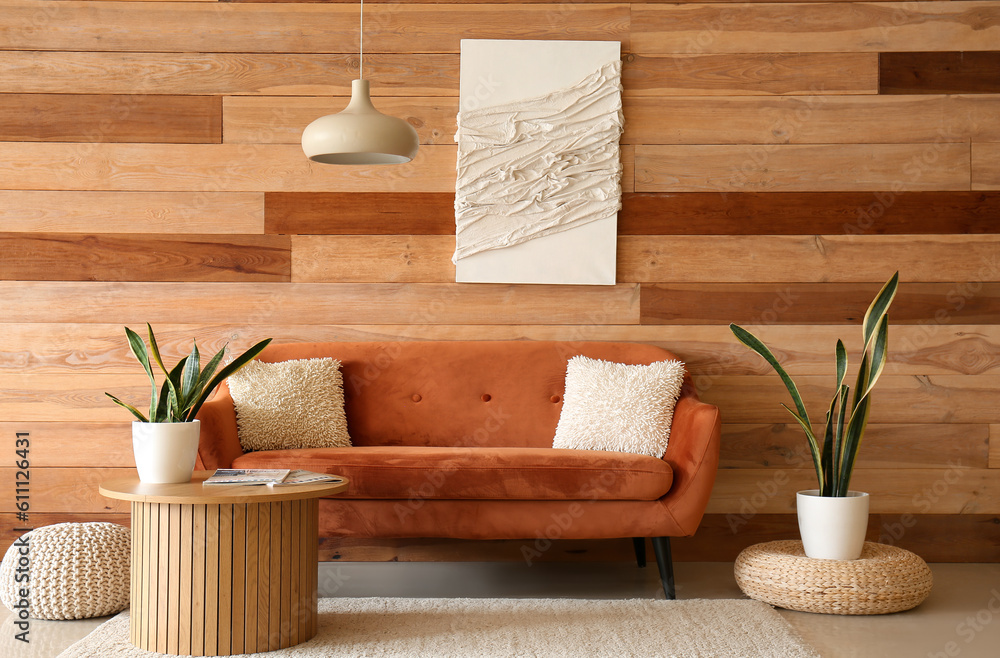 Cozy brown sofa with cushions and houseplant on coffee table in living room