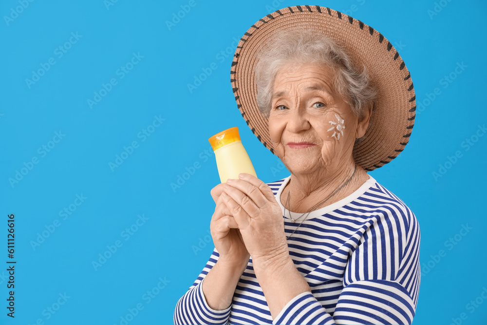 Senior woman with sunscreen cream on blue background