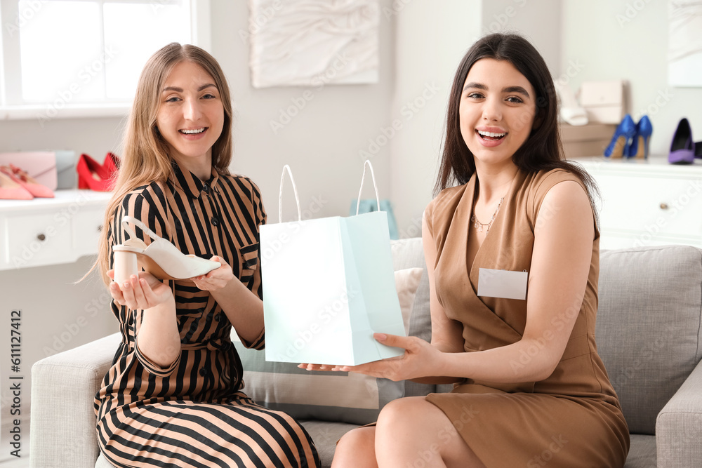 Female sales assistant giving bag with shoes to customer in shop