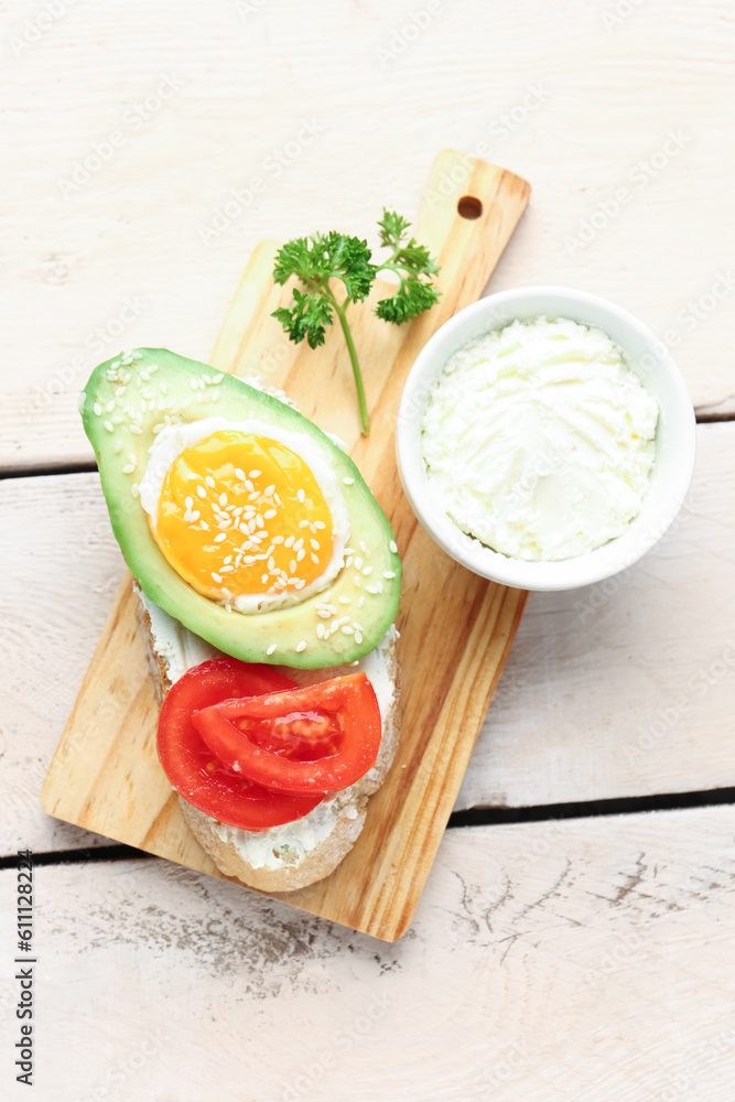 Board of tasty bruschetta with avocado and cream cheese on light wooden background