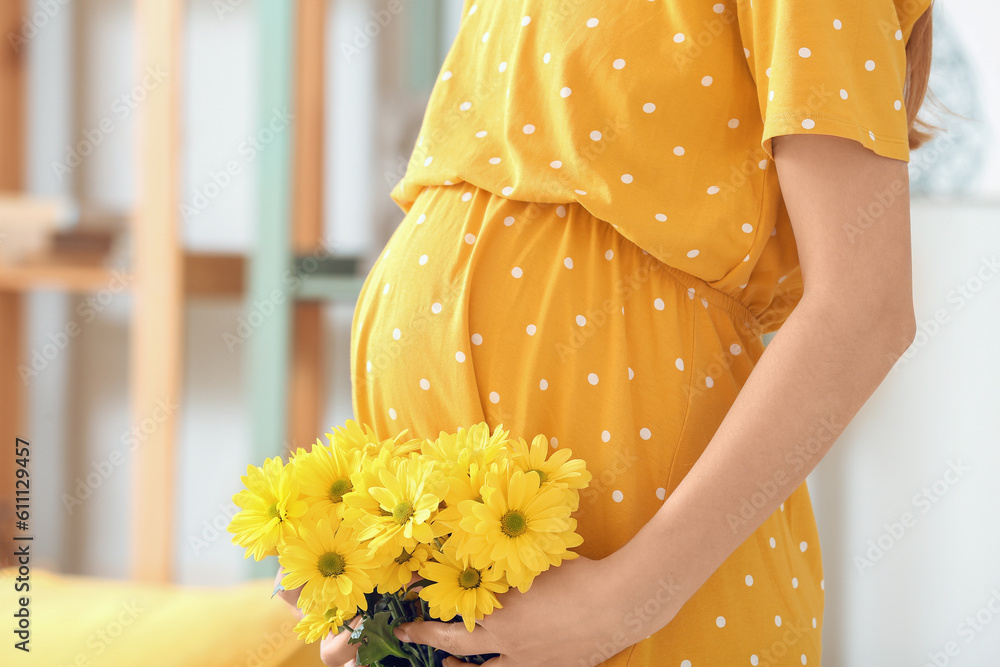 Young pregnant woman with chrysanthemum flowers at home, closeup