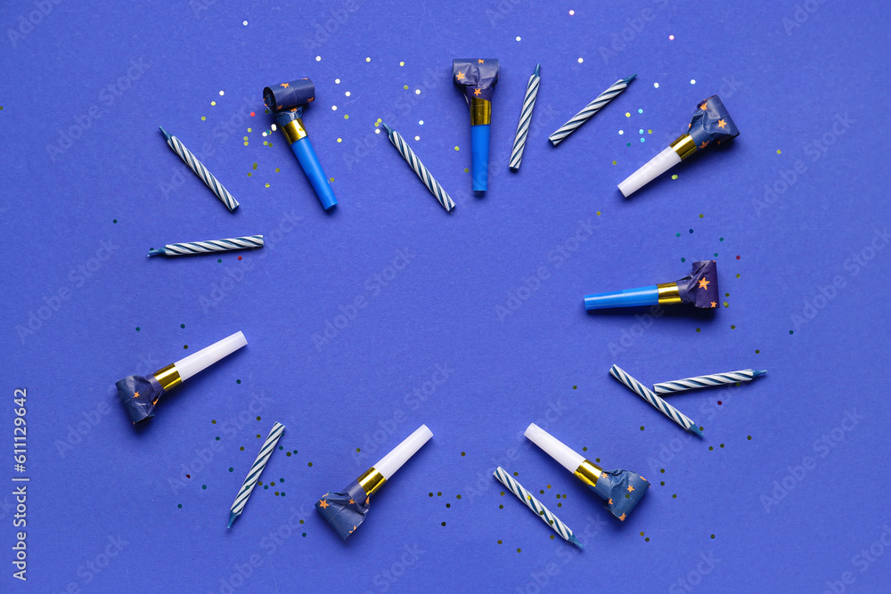 Frame made of whistles and candles for birthday party on dark blue background