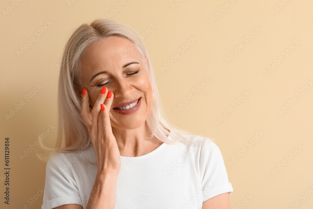 Mature blonde woman on beige background, closeup