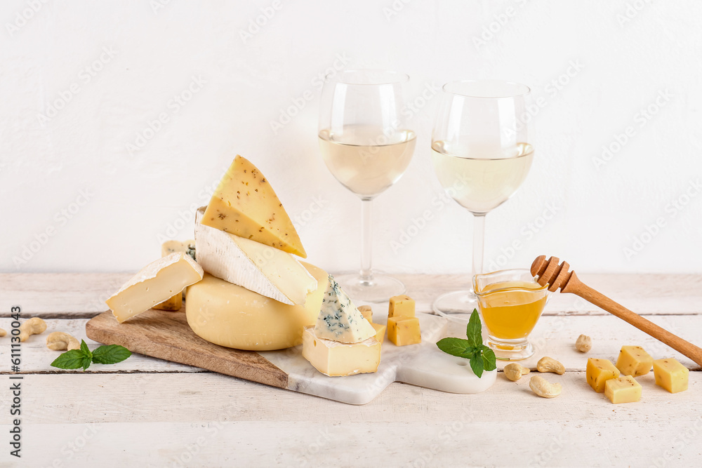 Different types of tasty cheese, honey and glasses with wine on table