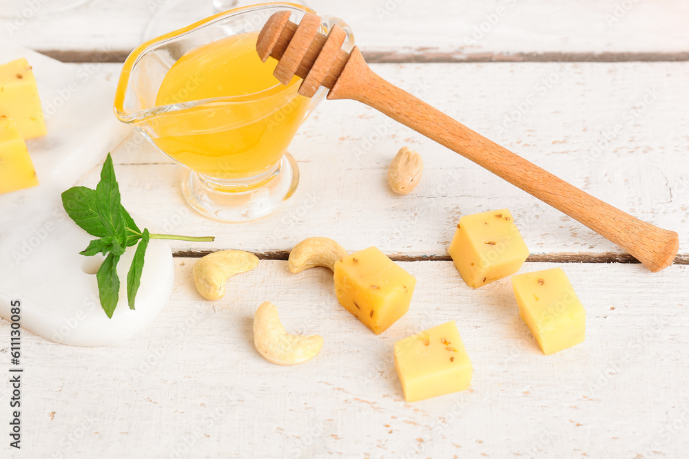 Pieces of tasty cheese with honey on light wooden background