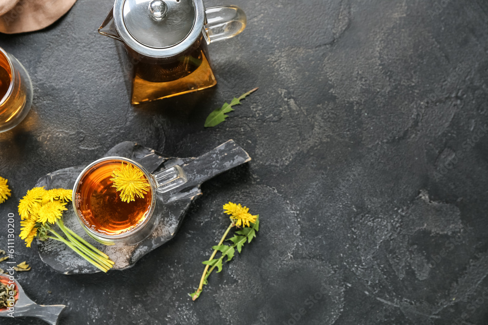 Glass cups of healthy dandelion tea and teapot on black background