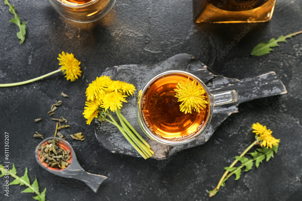 Glass cup of healthy dandelion tea on black background