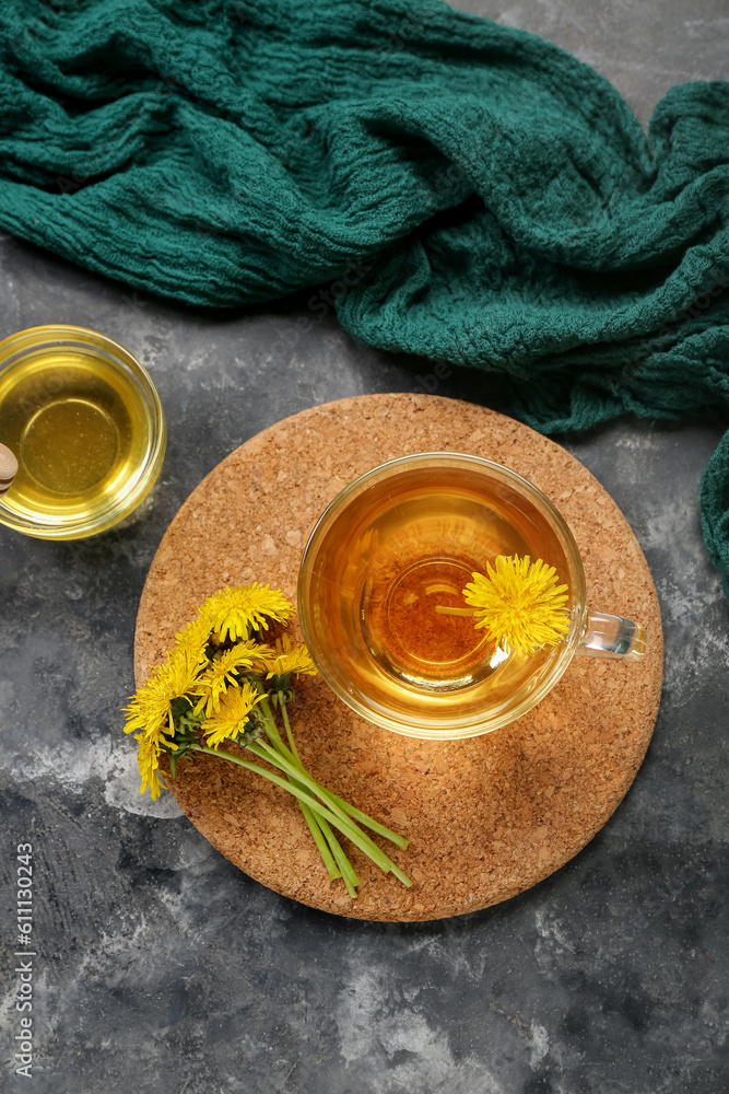 Board with glass cup of healthy dandelion tea on grey background