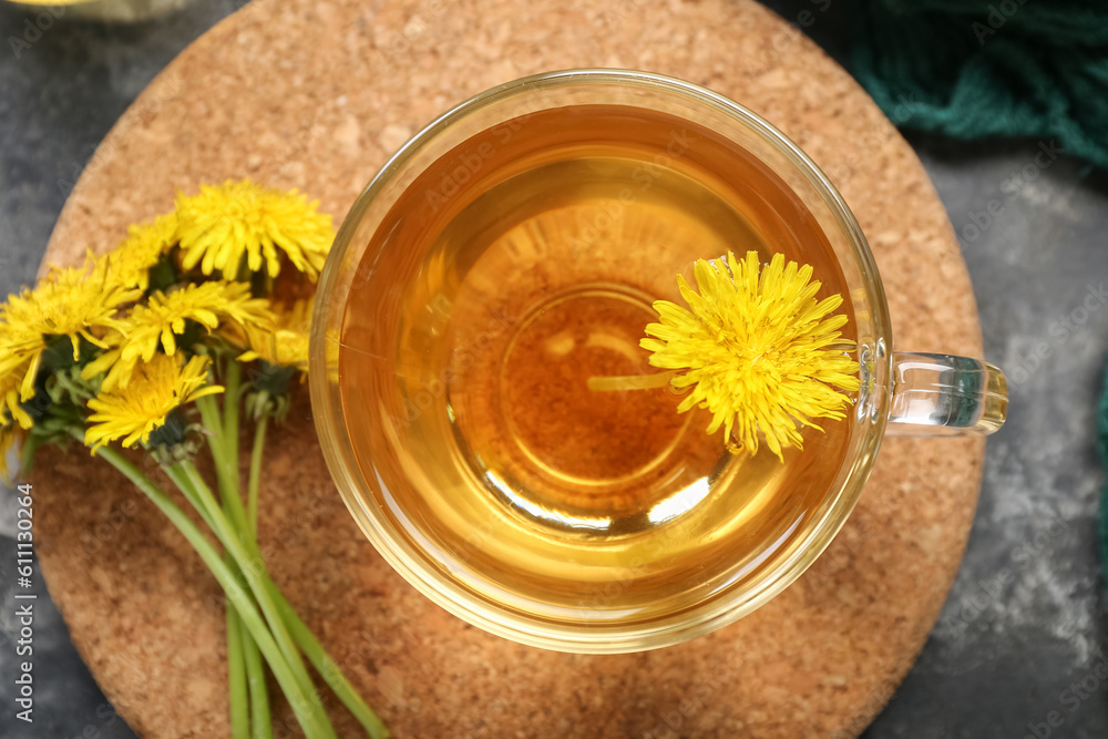 Board with glass cup of healthy dandelion tea on grey background