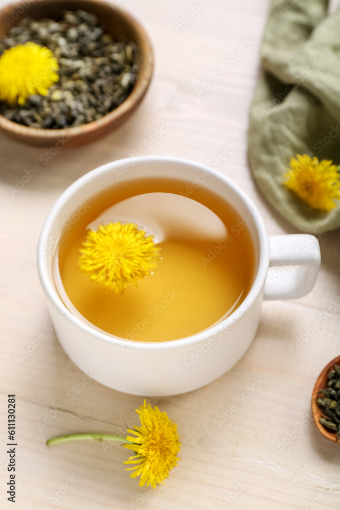 Bowl and cup of healthy dandelion tea on white wooden background