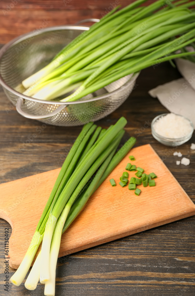 Board with fresh green onion on wooden background