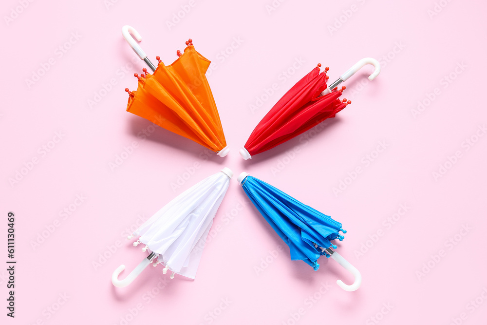 Different mini umbrellas on pink background