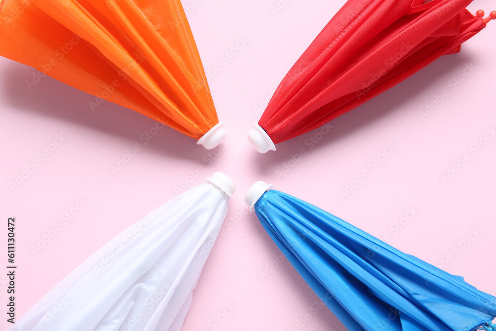 Different mini umbrellas on pink background