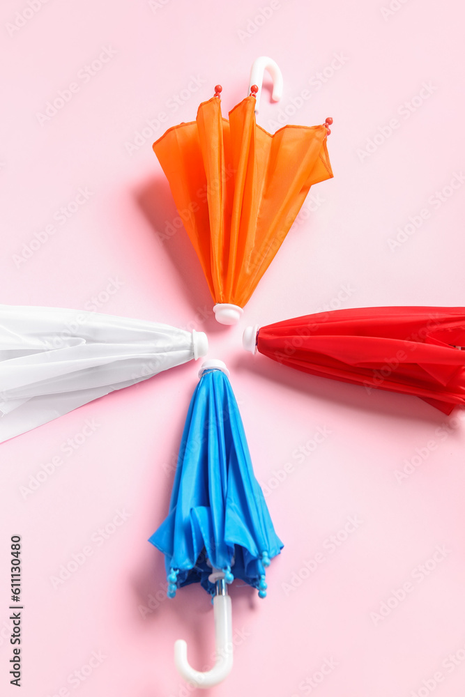 Different mini umbrellas on pink background