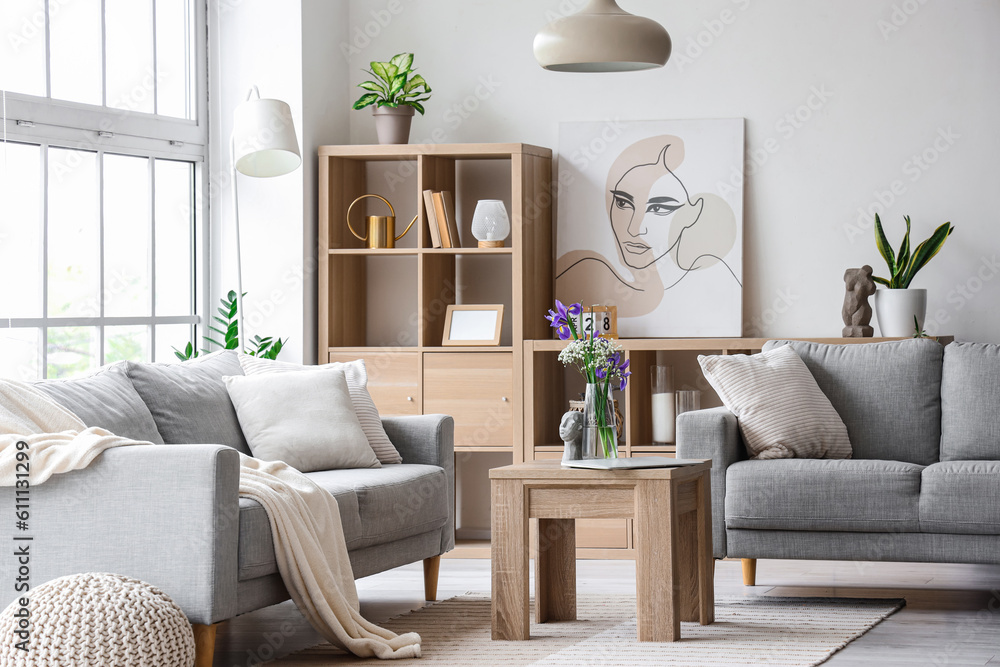 Interior of light living room with grey sofas and big window