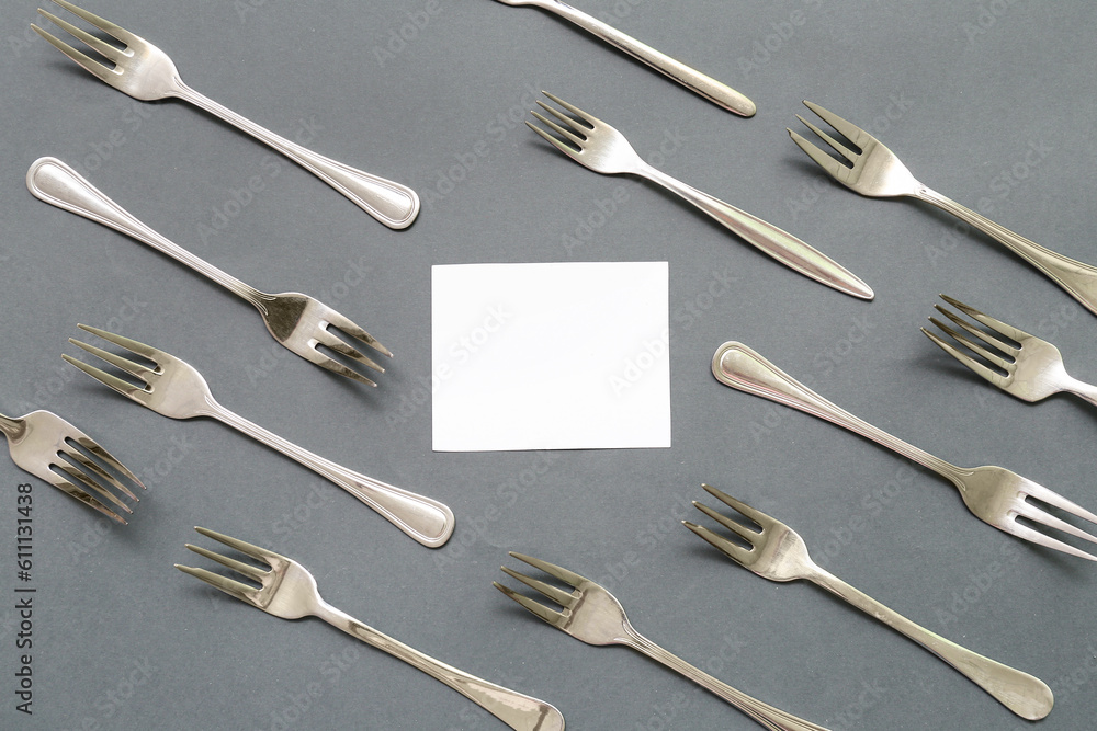 Composition with blank card and stainless steel forks on color background