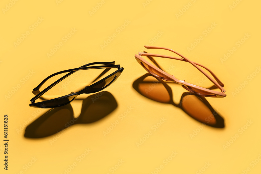 Stylish sunglasses on yellow background