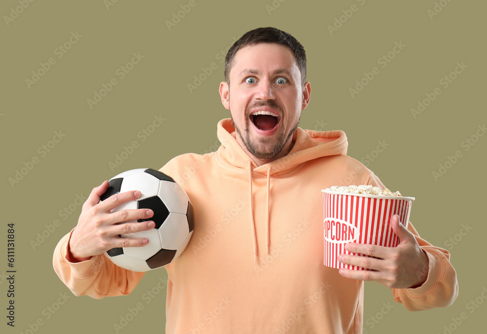 Screaming soccer fan with ball and popcorn on color background