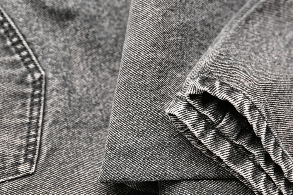 Stylish grey denim jeans as background, closeup