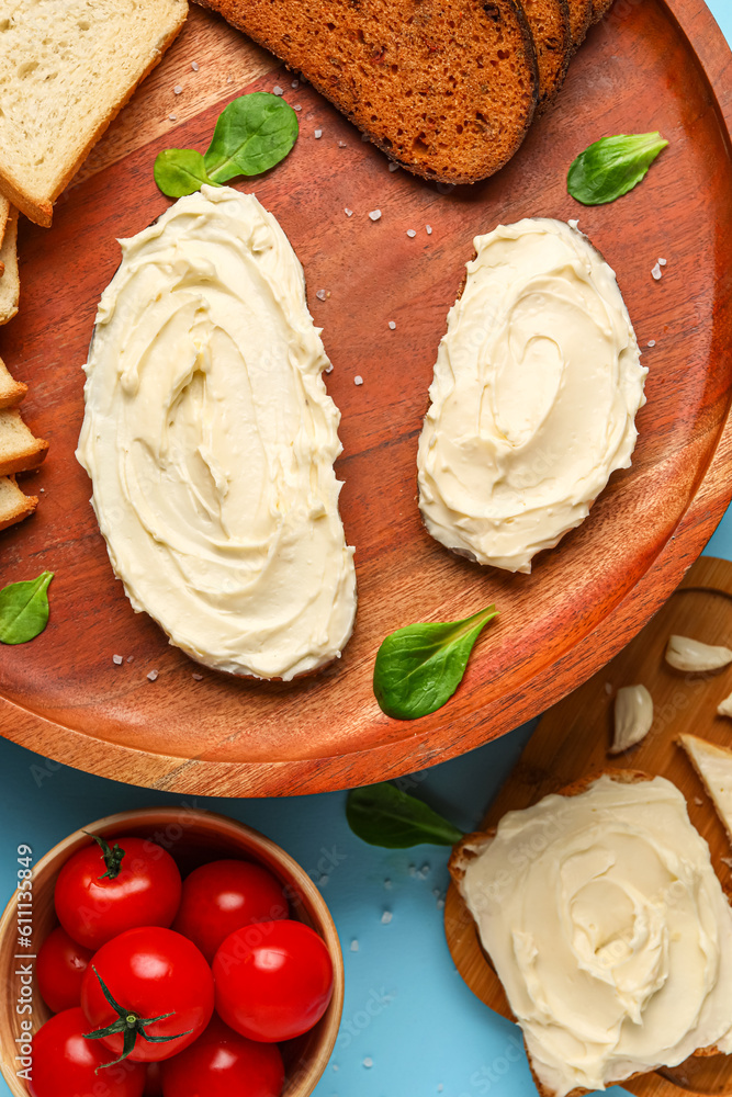 Tasty sandwiches with cream cheese on blue background