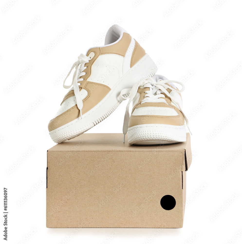 Cardboard box with stylish sneakers on white background