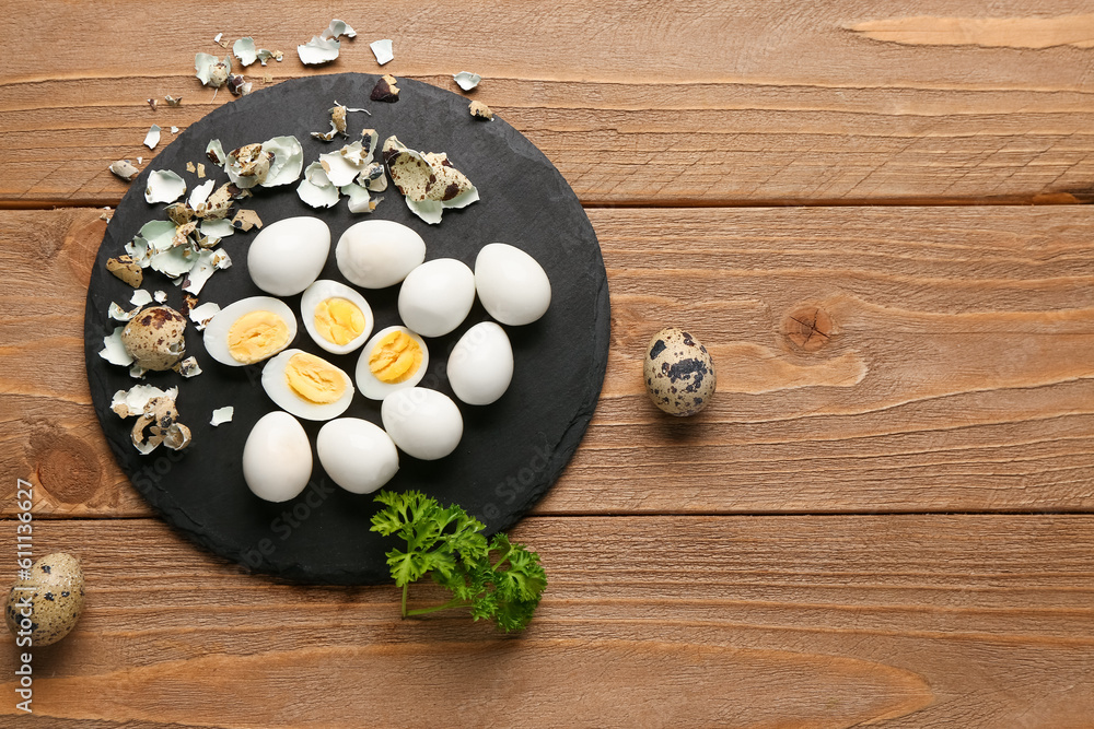 Board of boiled quail eggs with shells on wooden background