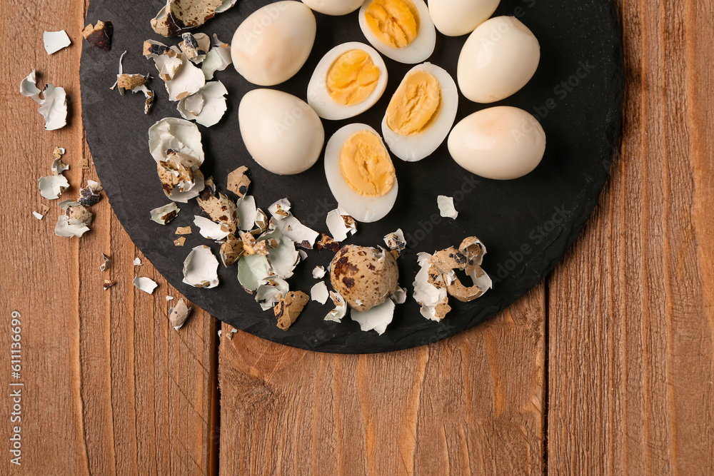 Board of boiled quail eggs with shells on wooden background