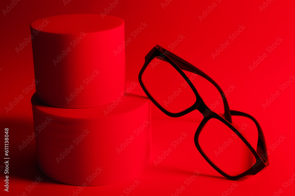 Podium with stylish sunglasses on red background