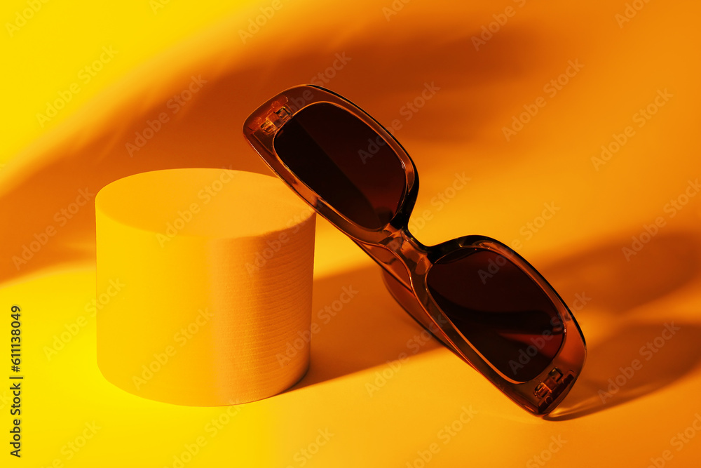 Podium with stylish sunglasses on orange background