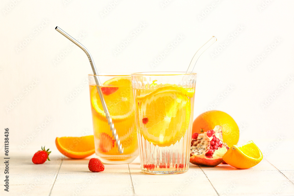 Glasses of infused water with orange slices on white tile table