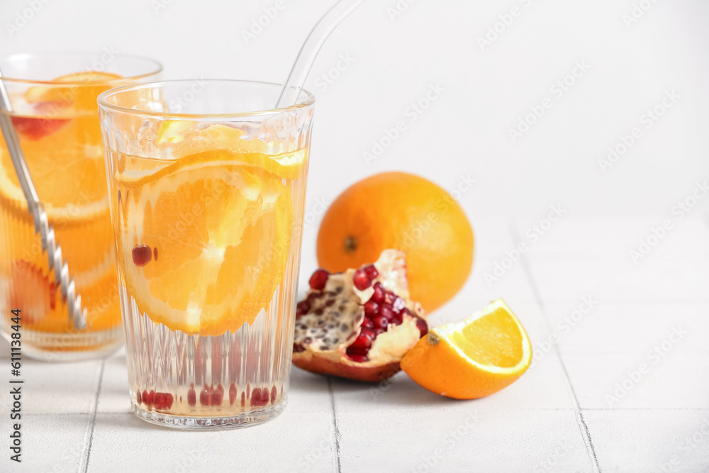 Glasses of infused water with orange slices on white tile table