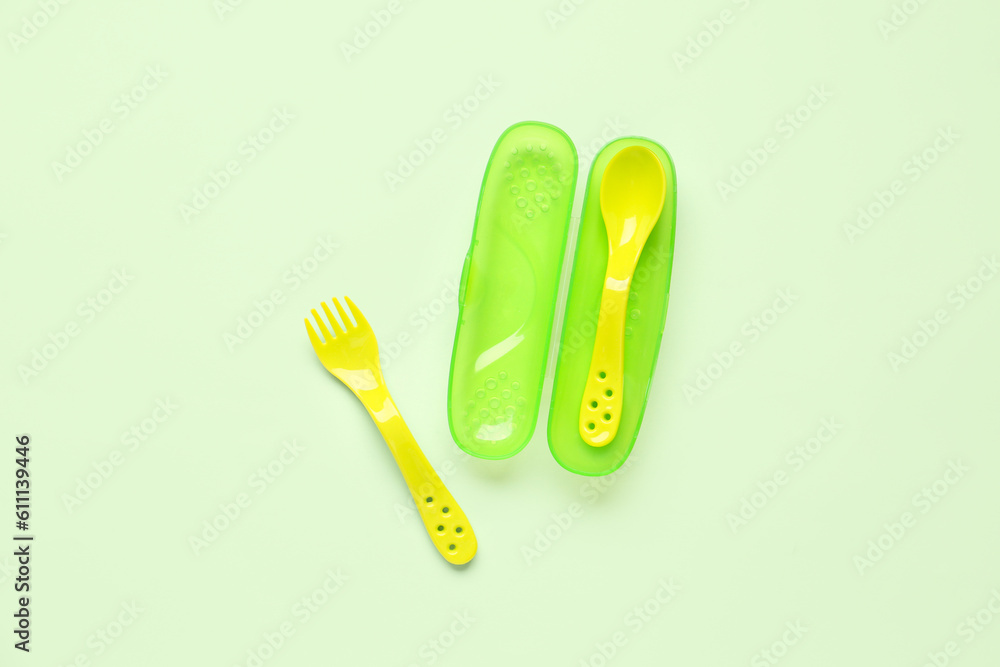 Yellow eating utensils for baby on pale green background